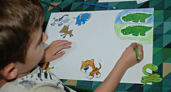 Creating his own zoo map using cut out figures