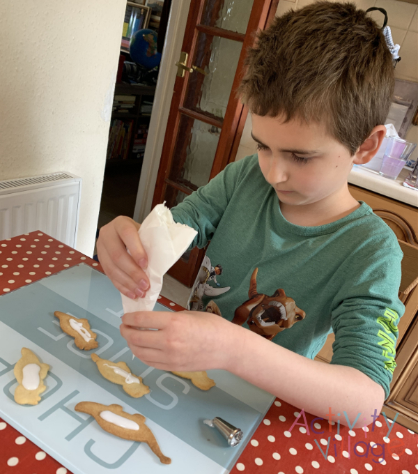 Using an icing nozzle on his dinosaur biscuits