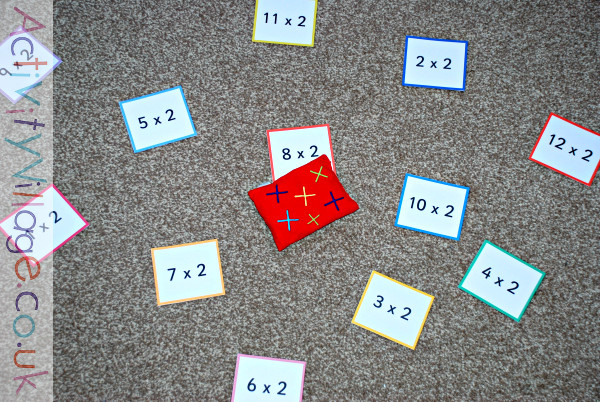 Playing a times tables game with double-sided flash cards and a bean bag