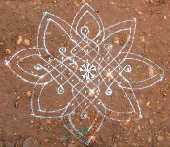 Simple rangoli design drawn with rice powder in the dirt